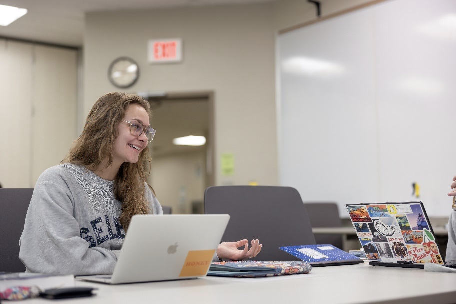 a female student sitting at a table with a laptop